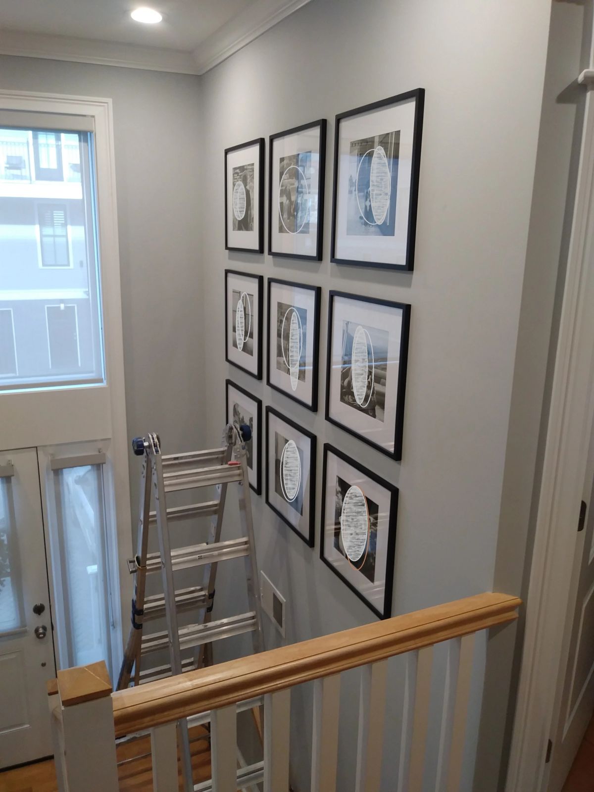 Nine equally-sized black frames mounted in a grid on a stairway wall